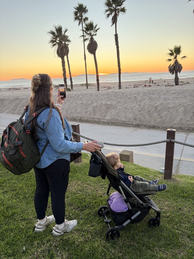 Mother Capturing Sunset Moment with Child at Beach