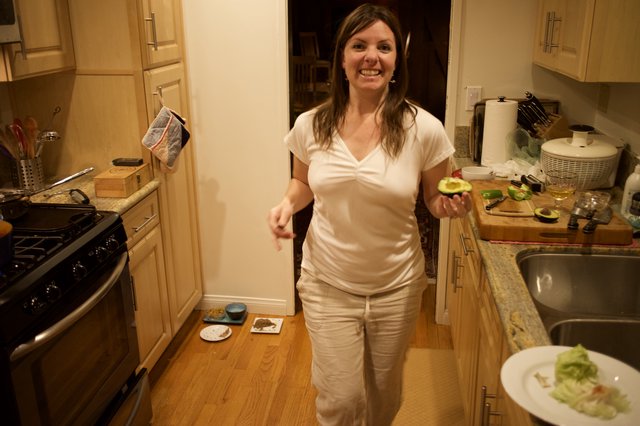 Woman Holding Fresh Avocado in Cozy Kitchen