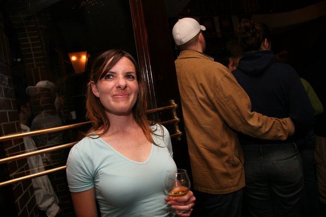Woman Smiling at Social Gathering in Dimly Lit Bar