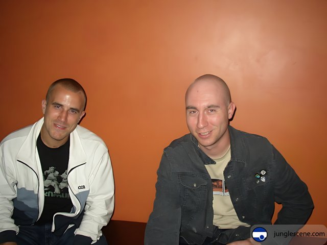 Two Men Sitting in Front of an Orange Wall