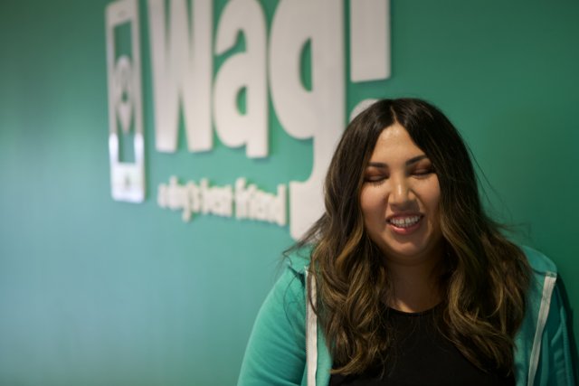 Happy Woman Poses in Front of WAG Logo