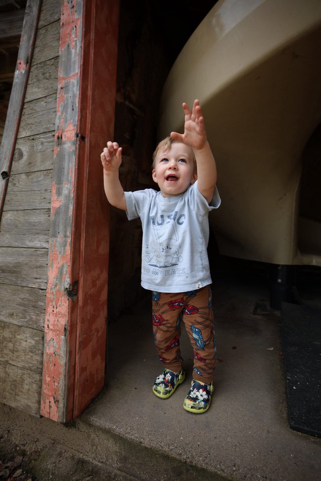 Joyful Toddler Reaching Up in Rustic Doorway