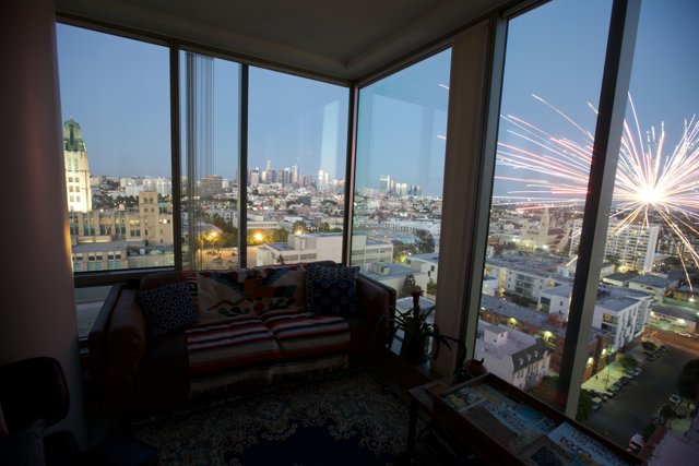 Fireworks illuminating the city sky from a penthouse window
