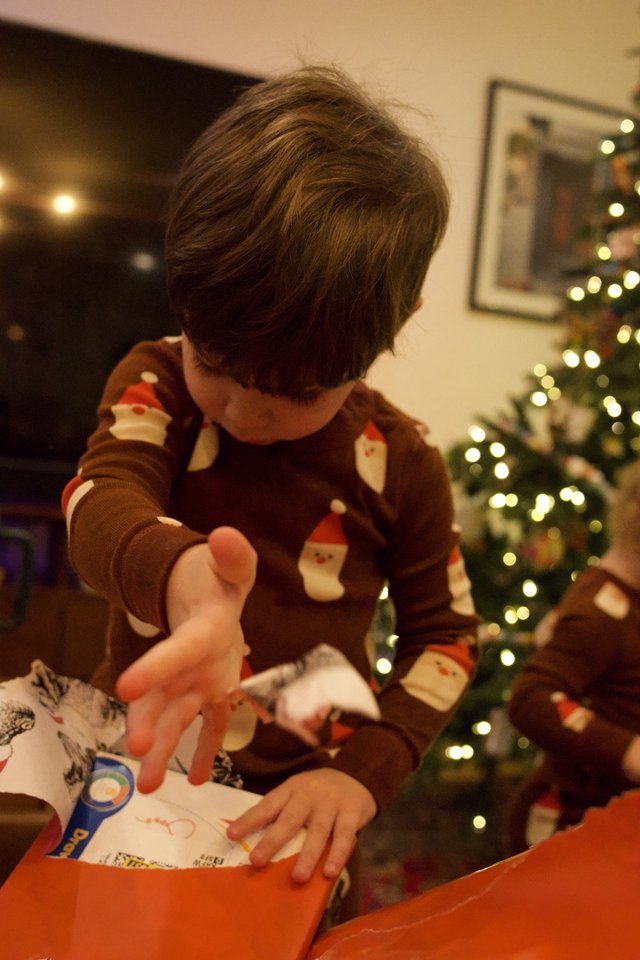 Child Opening Christmas Presents by the Tree