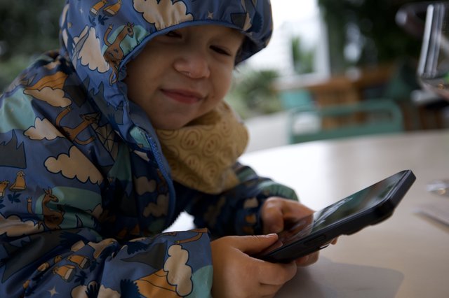 Young Child with Phone at Outdoor Dining Area