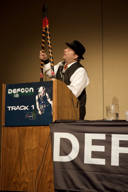 Microphone in Hand Caption: A man holds a microphone while addressing the crowd at Defcon 18.