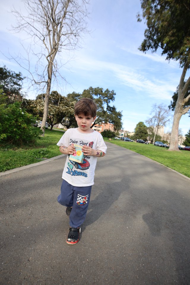 Young Boy Walking Through Park with Snack