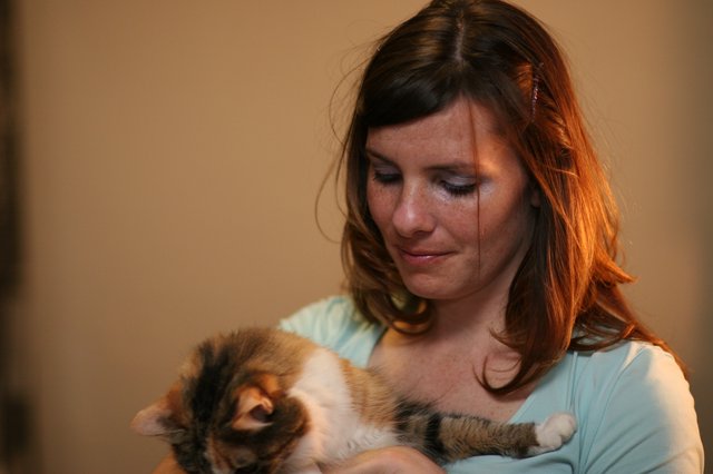 Tender Moment: Woman Cradling Sleeping Kitten