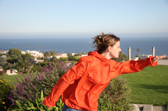Woman in Orange Jacket Embracing Ocean Breeze