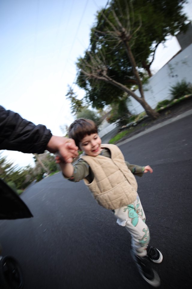 Child Walking Hand-in-Hand on Suburban Street