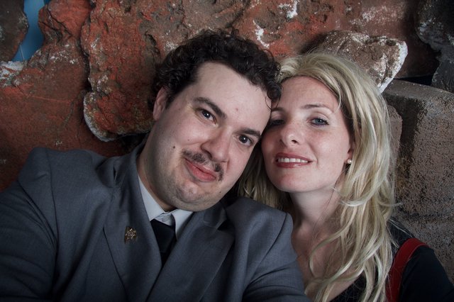 Couple Poses Warmly Against Rustic Brick Wall