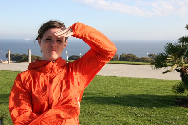 Woman in Orange Jacket Shielding Eyes by Ocean