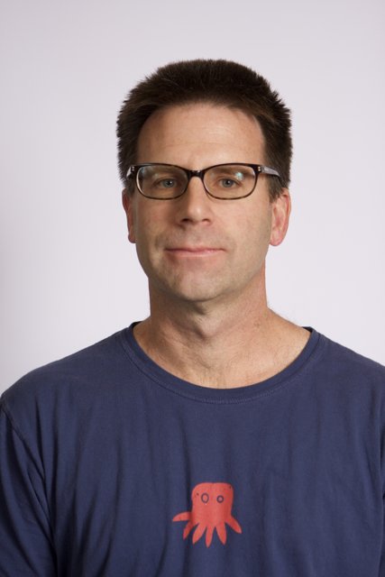 Smiling Man in Blue T-Shirt and Glasses