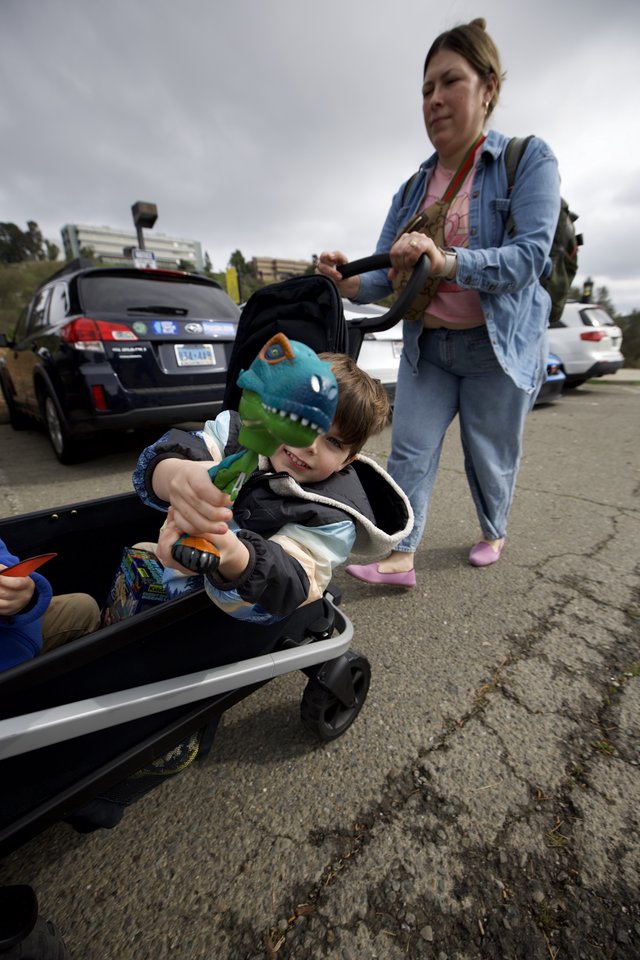 Mother Pushing Child in Wagon Through Parking Lot