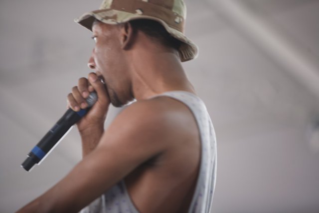 Sam R performs with a microphone and a hat at Coachella 2011