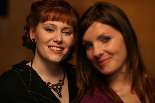 Two Smiling Women at an Indoor Social Gathering
