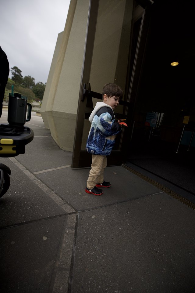 Young Boy Peering Through Glass Storefront Door