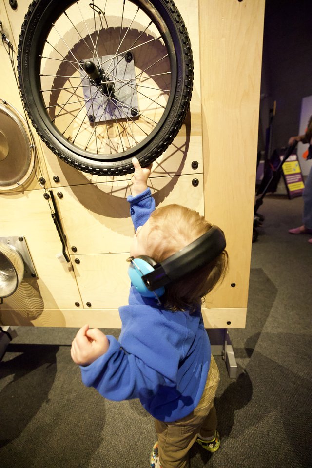 Young Child Explores Interactive Bicycle Wheel Exhibit