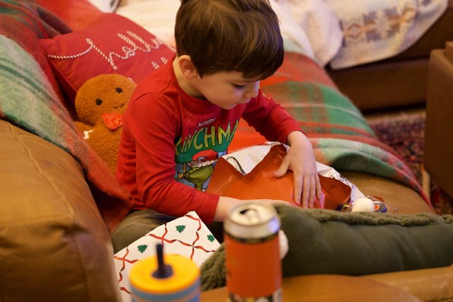 Young Boy Opening Christmas Presents in Cozy Living Room