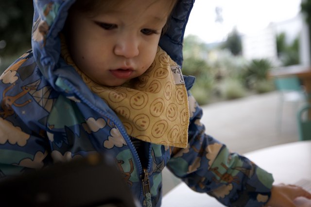 Young Child in Patterned Raincoat with Smiley Bib