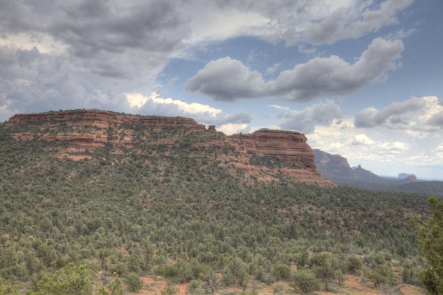 Majestic Red Rocks and Lush Trees Under the Cloudy Sky