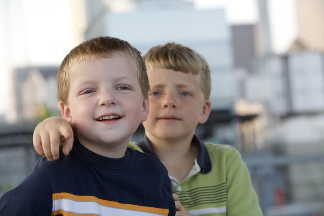 Two Boys Grinning with City Skyline