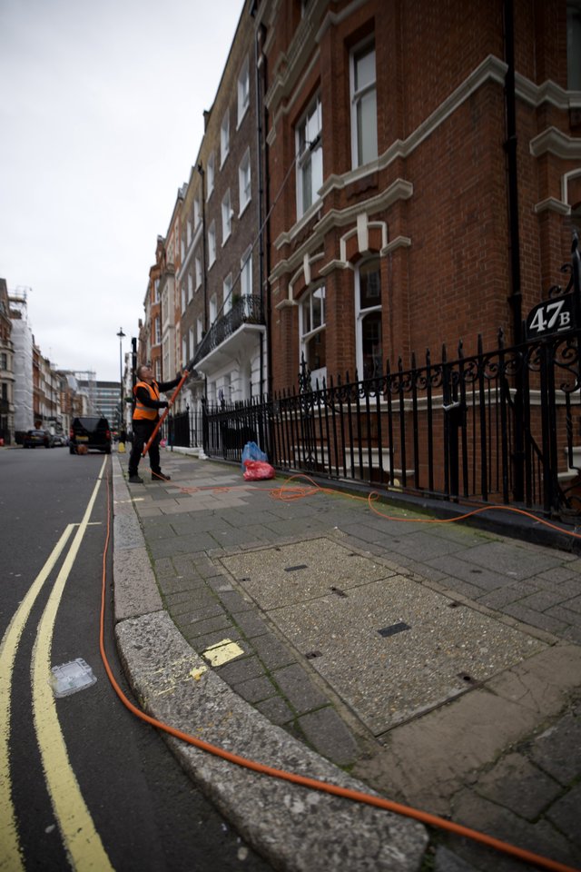 Utility Worker Pressure Washing London Street Sidewalk
