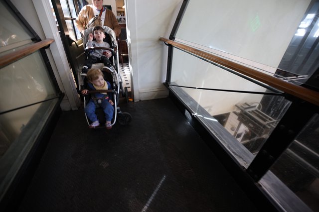 Parent Navigating Double Stroller Through Historic Building Hallway