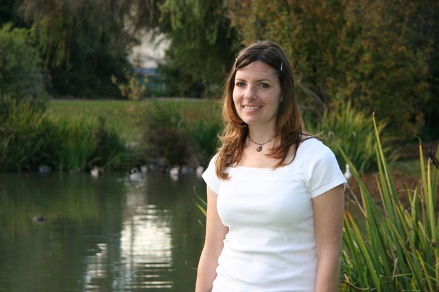 Young Woman Smiling by a Tranquil Park Pond