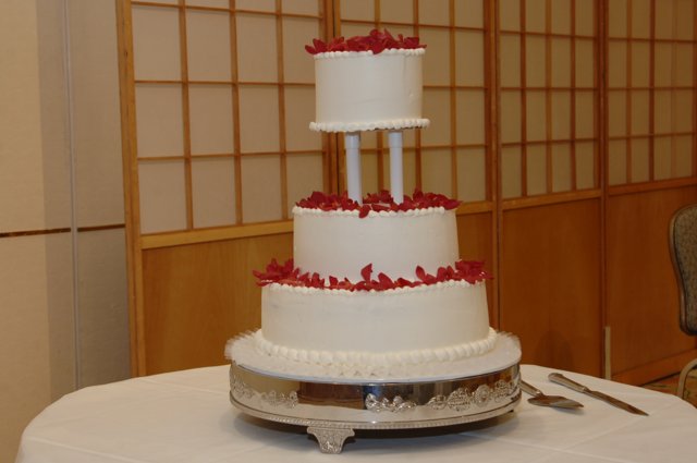 Elegant Three-Tiered Wedding Cake with Red Flowers