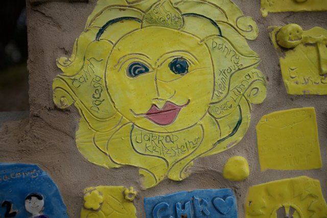 Yellow Sun Face Mural on Building Wall