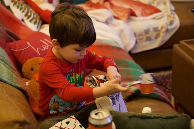 Young Child Opening Christmas Presents on Cozy Couch