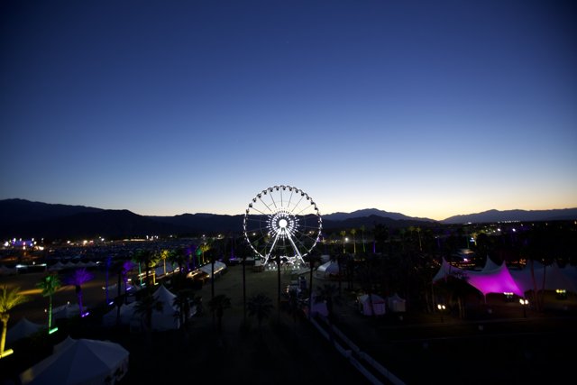 The Glowing Ferris Wheel against Majestic Mountains