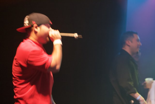 Entertainer Takes the Stage with Microphone and Baseball Cap