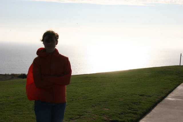 Windswept Woman in Red Overlooking Coastal Cliffs