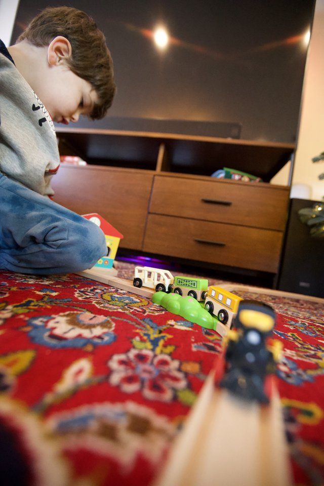 Child Playing with Wooden Train Set on Ornate Rug