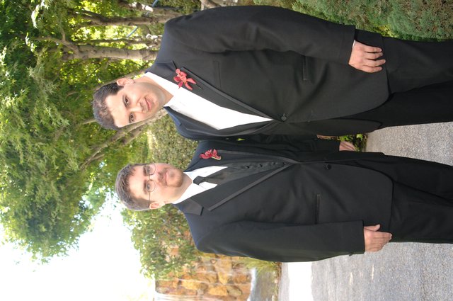 Two Groomsmen Posed in Black Tuxedos Outdoors