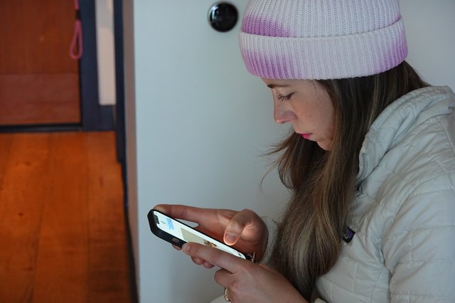 Young Woman Using Smartphone in White Puffy Jacket