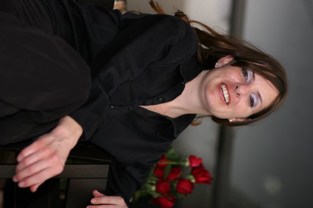 Smiling Woman in Black Amid Red Roses
