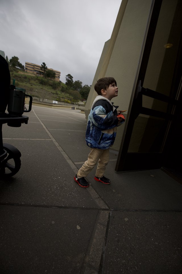Young Boy Looking Up at Bus on Overcast Day