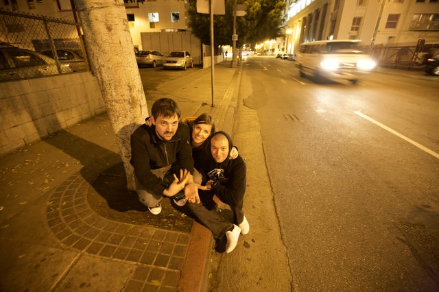 Three Friends Celebrating on City Sidewalk at Night