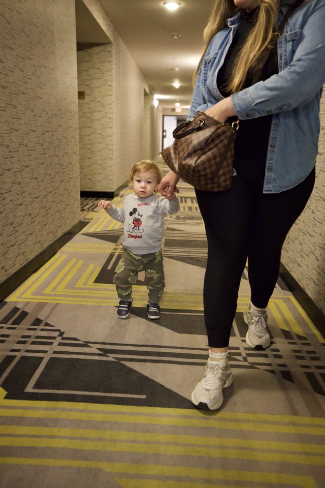 Toddler and Mother Walking Through Hotel Corridor
