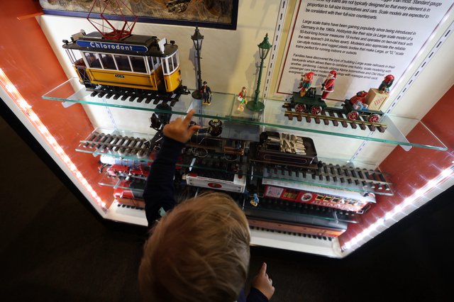 Child Exploring Vintage Train Models at Museum Display