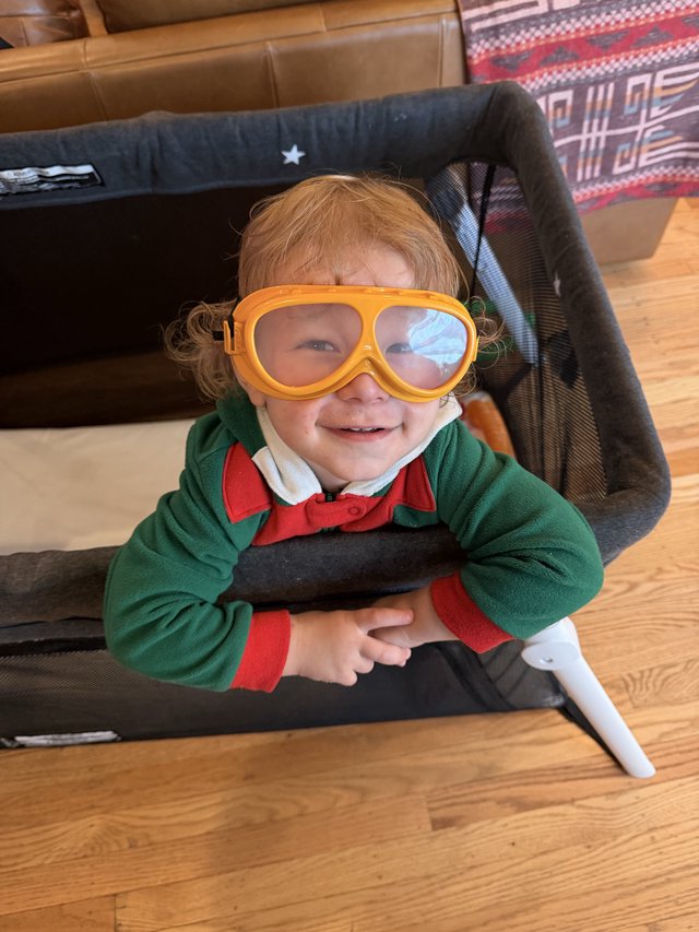 Cheerful Child in Orange Goggles and Green Jacket