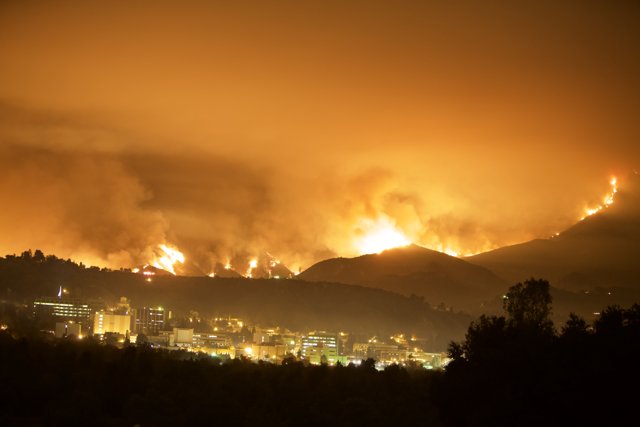 Flames Engulf the Hills Above a City