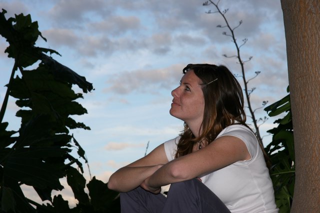 Woman Gazing Upward at Dusk Amid Tropical Foliage