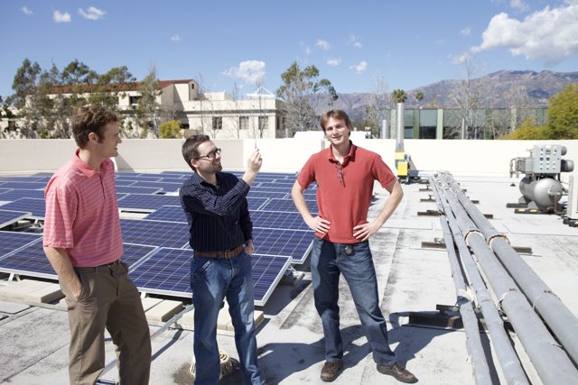 Three Men Working on Solar Panels on Rooftop