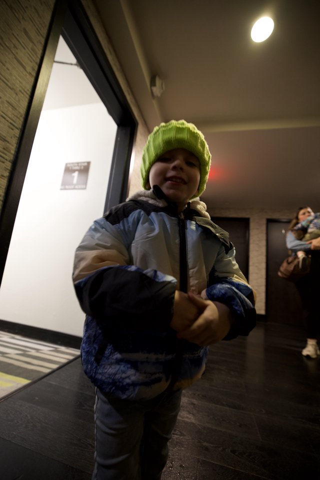 Cheerful Child in Bright Green Beanie at Building Entrance