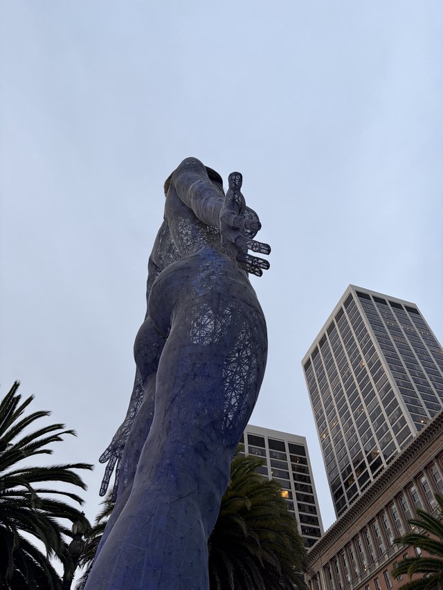 Towering Goddess Statue Against Urban Skyline