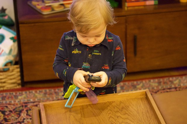 Toddler Playing with Toy Cars on Wooden Tray